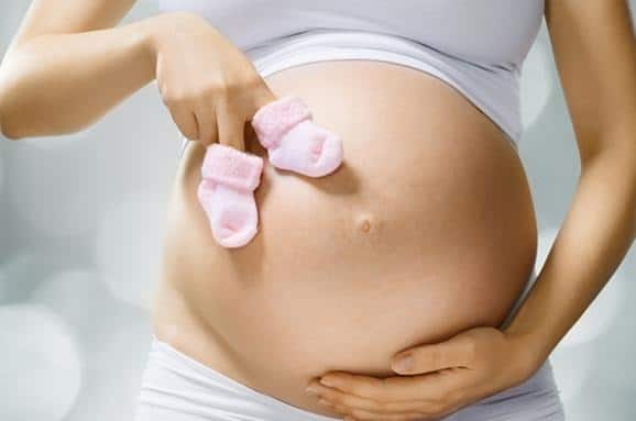 Ostéopathe manipulant doucement une femme enceinte dans un cabinet ostéopathie pour soulager les tensions et préparer l’accouchement